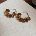 Detail of amber resin bead hoop earrings on beige linen fabric with silver needles - Coffee
