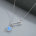 Detailed macro view of heart-shaped blue zircon pendant with diamond-set safety pin chain - Silver Blue