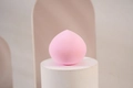 Close-up of a soft pink teardrop-shaped makeup sponge on a minimalist geometric background - Classic Pink Waterdrop