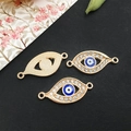 Macro view of blue evil eye and leaf gold charms with inlaid rhinestones on black background - KC Gold Evil Eye 12x27mm