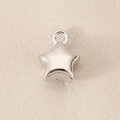 Macro shot of silver star pendant charm with a polished metallic finish and smooth loop - Star Silver (White K Plated)