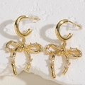 Macro view of gold bow-shaped earrings with crystals on a textured white stone surface - Bowknot Rhinestone Earrings (ES2387-5)