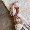 Detalle de bufanda de punto rosa con flores naranjas y pompones de piel sintética blanca - Rosa