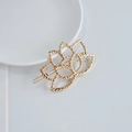 Pince à cheveux lotus dorée minimaliste avec texture métallique sur disque blanc - Lotus Creux