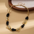 Dettaglio di perle in acrilico su una catena dorata con trame metalliche vintage - Nero