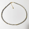 Macro detail of natural dalmatian jasper stone necklace with 925 silver heart tag - Beige Black Spotted Stone