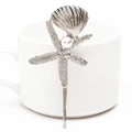 Silver starfish and seashell hair clip with white pearl detail on a white cup - Silver Conch