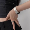 Polished stainless steel wide faceted bangle and wavy ring set on a model in black - Silver