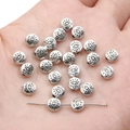 Close-up of silver alloy heart eye charms for DIY jewelry making held in a hand - Evil Eye Round Bead / 6mm