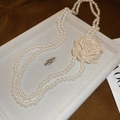 Dettaglio della collana di perle a doppio filo con una grande rosa in tessuto nel vassoio - Collana-Fiore Bianco