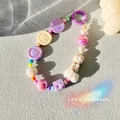 Détail d'un pendentif en perles avec oursons en résine macaron et pompons blancs - Violet