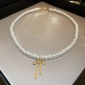 Detailed view of pearl necklace featuring a gold bow pendant on high-quality display board - Gold Bowknot Pearl Necklace