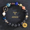 Macro detail of Aries zodiac bracelet with lava rock, blue sandstone and gold charms - Aries