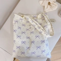 Detailed flat lay of floral canvas tote bag with purple bows and a minimalist textile label - White Base Light Purple Bow