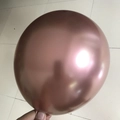 Hand holding a 10-inch rose gold metallic latex balloon for party decorations - Rose Gold