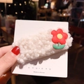 White fuzzy plush hair clip with red flower accent on a display card in a warm setting - J-19-Hyuna Flower