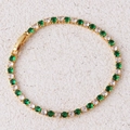 Detail van een gouden tennisarmband ingelegd met groene en witte zirkonia steentjes - Groene Armband-Goud