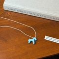 Dettaglio di un ciondolo a forma di pony blu con cordino bianco su uno sfondo in legno - Stile Cavallo Blu (6120361027610) / Blu