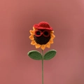 Handmade crochet sunflower doll wearing a red hat and black sunglasses on pink background - Cartoon Sunflower Red