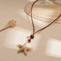 Collana con ciondolo a stella marina con cordino marrone e perla in legno su sabbia - Collana Stella Marina