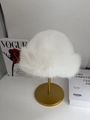Chic white faux fur bucket hat displayed on a gold stand for winter warmth - Bleached White