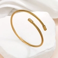 Elegante bracciale rigido a torsione dorato con punte sferiche su una pietra bianca testurizzata - Oro
