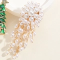 Makroaufnahme einer floralen Perlenbrosche mit Goldmetallakzenten und Quasten - Gewebte Perlenquaste