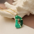 Detailed close-up of a green enamel letter D pendant with gold chain on a textured surface - Letter D