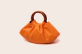 Detailed view of an orange pleated cloud bag with a dark brown wooden round handle - Orange