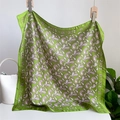 Close-up of green paisley silk scarf with SUN border hanging on wooden clips - 70x70cm / Green
