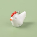 Close-up of a 3D white resin duckling pendant with red comb and metal ring loop - Chicken
