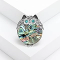 Retro owl brooch with silver metal filigree and iridescent abalone shell on white display - Silver