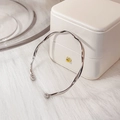 Bracelet jonc Mobius argenté torsadé posé sur une boîte à bijoux et un tapis en peluche - Extrémités à billes ouvertes torsadées / Argenté