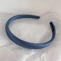 Detail view of handmade blue satin headband with woven label on soft white paper - Morandi Blue