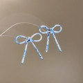 Détail de boucles d'oreilles nœud en acétate avec texture marbrée bleue sur support clair - Marbre Bleu Blanc