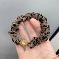 Detail eines Haargummis mit Leopardenmuster und einer goldenen Strasskugel-Verzierung - Organza Leopard