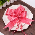 Detail view of a large red wedding bow with embossed rose patterns on a white decorative plate - Red Rose Print