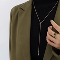 Detail of a gold knot pendant necklace paired with a green emerald ring on a model - Gold Snake Chain Double Knot