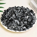 Natural black and gray spotted crystal chips displayed in a white plate for aromatherapy - 100g Of Alabaster (7-9mm)