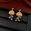 Detailed shot of golden hollow earrings with clear tassels on black leather stand - Gold