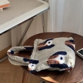 Dettaglio della borsa in lana d'agnello peluche con stampa astratta su sgabello in legno - Piccola borsa a mano aperta