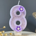 Sparkling purple number 8 birthday candle with 3D floral accents on a wooden base - Number 8