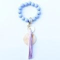 Close-up of light blue beads with purple leather tassel and wooden disk on gold keychain - Blue