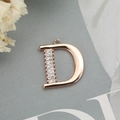 Détail macro du pendentif lettre D en or rose avec zircons rectangulaires sertis - Or rose