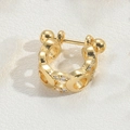 Macro shot of a golden C-shaped ear cuff with embedded clear gemstones on a textured surface - Hollow Style