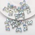 Macro view of 10x14mm iridescent butterfly glass beads on a white ceramic plate edge - Transparent Green