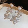 Close-up of elegant gold heart earrings with white textured petals in French vintage style - White