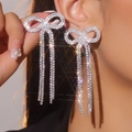Elegant silver bow earrings with long sparkling rhinestone tassels on model - Stud Earrings / Silver White Rhinestone