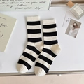 Classic black and white horizontal striped crew socks with ribbed cuffs on a white desk - Medium Stripe