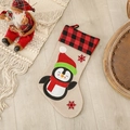 Weihnachtssocke aus beigem Leinen mit Pinguin-Applikation und kariertem Rand auf Holzboden - Pinguin-Stil